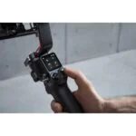 Hand holding DJI RS 3 gimbal stabilizer, ideal for video cameras and photography gear.