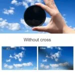 Hand holding a camera lens filter against a blue sky with clouds, demonstrating filter effect.