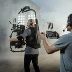 Professional videographers using advanced camera gear and stabilizers in a foggy setting.