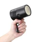 Hand holding Godox AD100Pro flashgun, ideal for professional photography lighting.