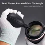 K&F Concept dust blower for camera lens cleaning, held by gloved hands.