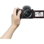 Sony mirrorless camera with flip screen displaying a smiling person, ideal for vlogging.