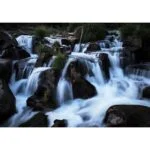 Flowing waterfall over rocks in a serene natural setting.