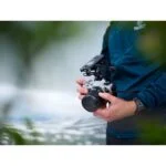 Person holding Olympus mirrorless camera with microphone attached.