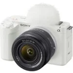 White Sony mirrorless camera with lens and microphone, ideal for vlogging and photography.