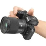Person holding Nikon mirrorless camera with Sigma lens, available at Camix UK.