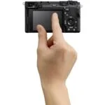 Hand holding a compact digital camera with touchscreen, available at Camix UK.
