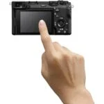Person interacting with a digital camera's touchscreen, showcasing camera features.