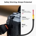 Camera safety strap with color-coded warning system for secure photography gear handling.