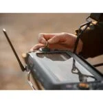 Close-up of a person operating a camera control device outdoors.