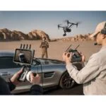 Photographers using drones and cameras in a desert setting, showcasing professional photography gear.