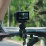 Action camera mounted on a bicycle handlebar for outdoor filming.