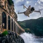 DJI drone flying near a rocky coastline with arches, capturing scenic views.