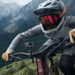 Mountain biker with action camera on handlebars in scenic landscape.