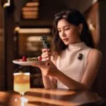 Woman using a compact camera in a cafe setting, capturing food photography.