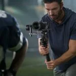 Photographer using a professional camera on a gimbal for sports photography.