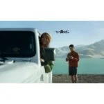 People using a drone near a lake, showcasing photography equipment.