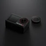 Compact action camera with detachable lens on a dark surface.
