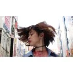 Person with dynamic hair flip in urban setting, showcasing vibrant city life.