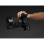 Hand holding a mirrorless camera with a large lens, ideal for professional photography.