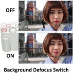 Woman demonstrating camera's background defocus switch feature in urban setting.