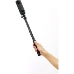 Hand holding a camera on a selfie stick, ideal for vlogging and photography.