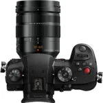 Top view of a Panasonic mirrorless camera with Leica lens, featuring control dials and buttons.