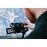 Person using a DSLR camera on a gimbal for video recording, showcasing photography gear.