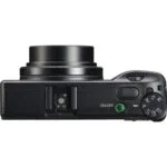 Top view of a compact digital camera with control dials and lens, available at Camix UK.