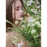 Woman holding a bouquet of wildflowers in a garden setting.