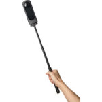 Hand holding a 360-degree camera on a selfie stick, ideal for capturing immersive photos and videos.