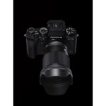 Fujifilm X-T4 mirrorless camera with lens, top view on black background.