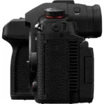 Side view of a professional mirrorless camera body with textured grip and control dials.