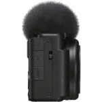 Side view of a compact digital camera with microphone attachment.