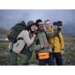 Group of friends taking a selfie with a camera in a scenic outdoor setting.
