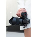 Person holding a Panasonic Lumix mirrorless camera with a wide-angle lens.