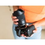 Person holding a Lumix camera and lens, showcasing photography gear.