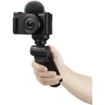 Sony digital camera with microphone on handheld tripod, ideal for vlogging and photography.