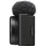 Side view of a compact digital camera with a microphone attachment.