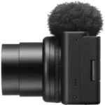 Side view of a compact digital camera with a microphone attachment.
