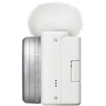 Side view of a compact white digital camera with a fluffy microphone cover.