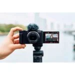 Person holding a Sony digital camera on a tripod, capturing a cityscape.