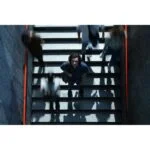 Person standing on stairs surrounded by blurred motion of people, captured from above.