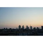 City skyline at sunset with modern buildings silhouetted against the sky.