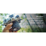 Person holding Olympus camera with M.Zuiko Digital ED 9-18mm lens, showcasing lightweight wide-angle photography.