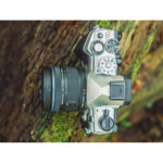 Mirrorless camera with lens on a wooden surface, ideal for photography enthusiasts.
