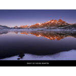 Scenic mountain landscape reflected in a calm lake at sunset.