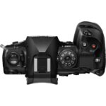 Top view of a black Olympus mirrorless camera body with control dials and buttons.
