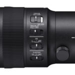 Close-up of a Sigma camera lens with focus and stabilization controls.
