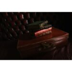 Vintage suitcase with old books on a leather chair, photography gear inspiration.